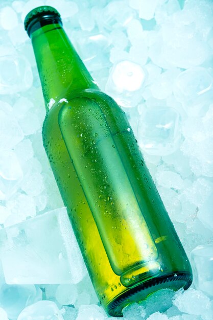 Foto bottiglia di birra verde in cubetti di ghiaccio molto fredda in verticale