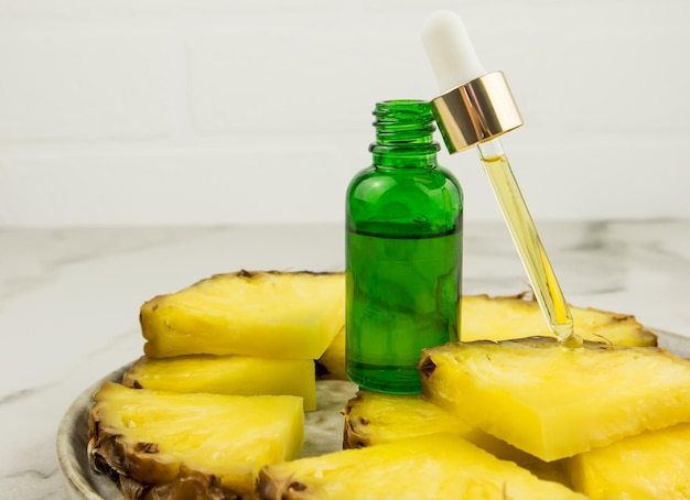 A bottle of green glass stands on pineapple slices with a cosmetic filled with a pipette. moisturizing natural cosmetics.