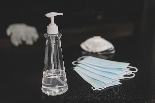 Photo bottle of hand sanitizer, hand disinfecting gel and surgical mask on dark background, crucial for coronavirus prevention through antibacterial hygiene