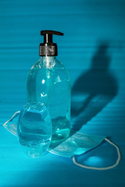 A bottle of hand sanitizer with a glass on a blue background