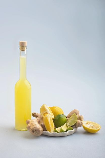 Bottle of homemade juice with ginger and lemon on blue background Vertical