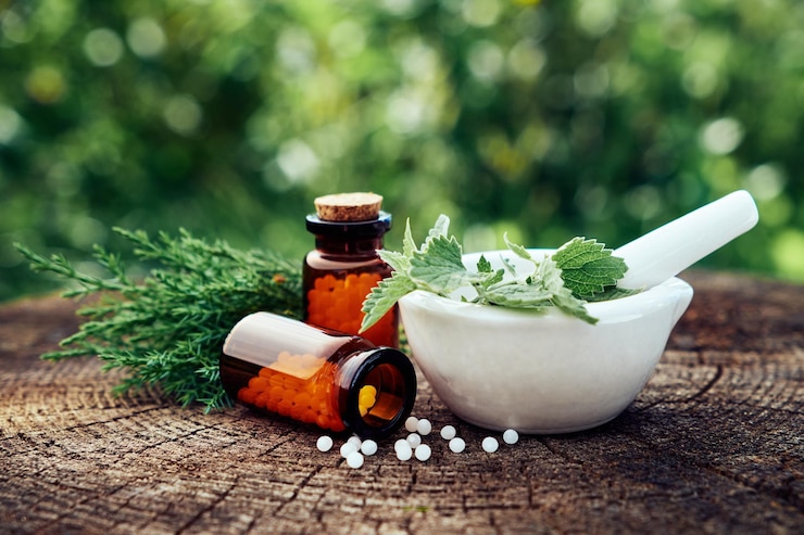 Photo bottle of homeopathic globules mortar of green nettle and mint leaves juniper twigs homeopathy