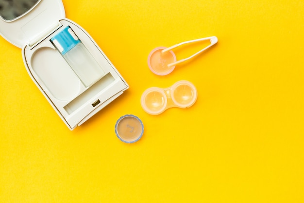 A bottle of liquid, a container and tweezers in a case on a yellow background