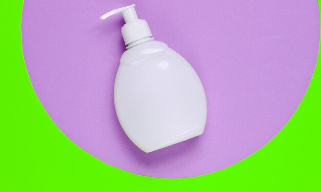 Bottle of liquid soap on on colored paper background with geometric shapes. Shower gel, shampoo. Pop art style. Top view