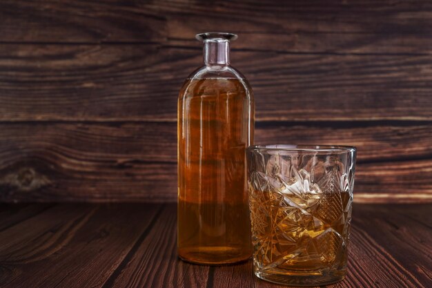 a bottle of liquor next to a cut glass with ice