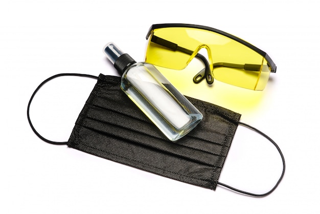 Bottle of lotion, sanitizer or liquid soap, protective goggles glasses and protective mask isolated on white wall with clipping path.