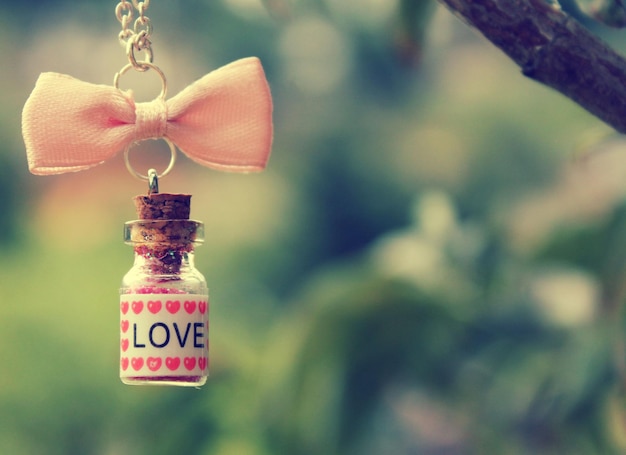 Photo a bottle of love is hanging from a tree branch