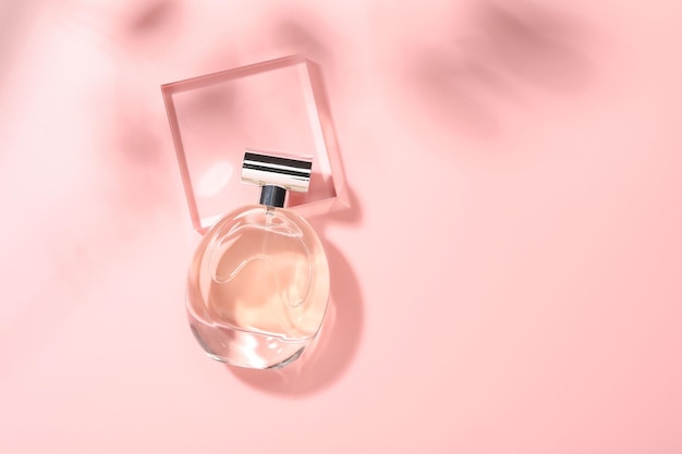 Bottle of luxury women39s perfume in sunlight on pink background top view Space for text