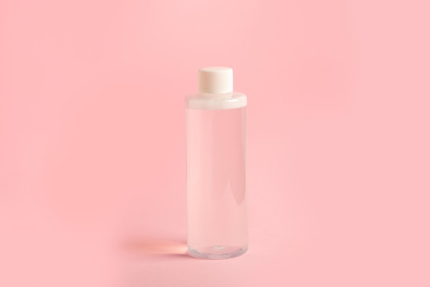 A bottle of micellar water stands on a pink background