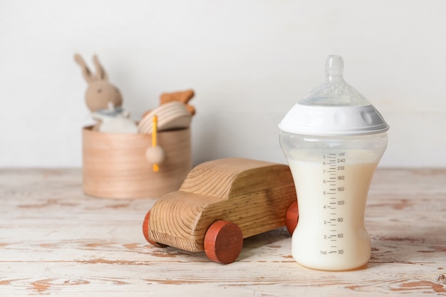 Bottle of milk for baby with toys on table