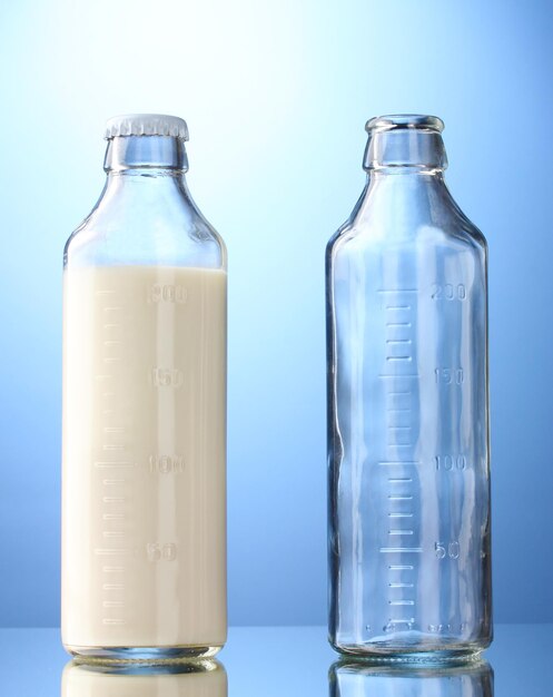 Bottle of milk and empty bottle on blue background