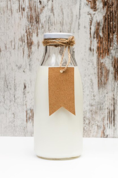 Photo bottle of milk with a blank cardboard label on a wooden background