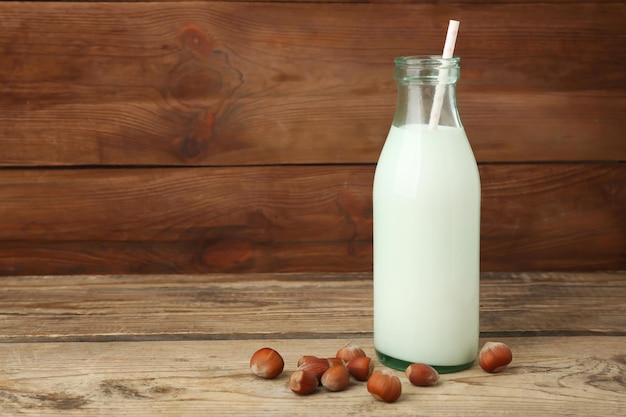 Bottle of milk with straw on wooden background