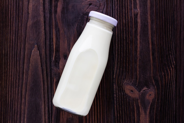 Photo a bottle of milk on wooden background.