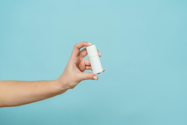 Bottle of nasal spray or eye drops in a female hand Copy space