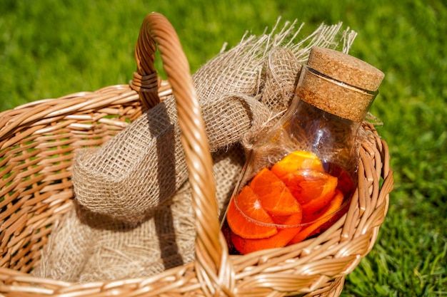 A bottle of natural homemade soda with berries and oranges pure organic food and drinks in a rustic style oranges juice and a basket on the green grass