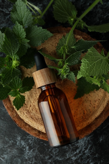 Bottle of nettle essence oil on black smokey table