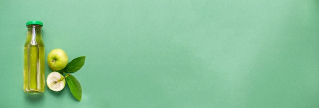 Фото Бутылка свежего яблочного сока фруктовый узор плоская планировка вид сверху зеленый фон с копией пространства