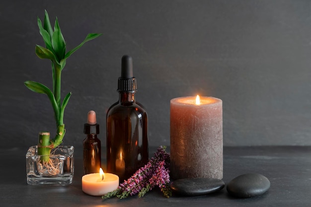 A bottle of oil next to a candle and a candle.