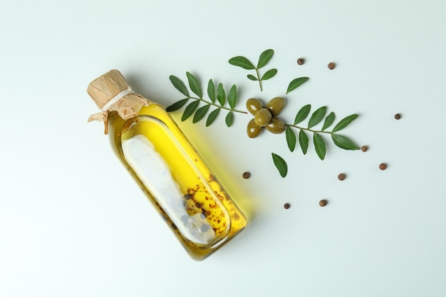 Bottle of oil, olives, twigs and pepper on white background