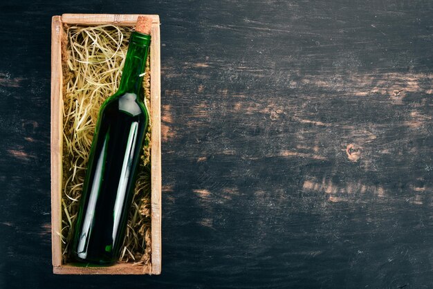 A bottle of old red wine in a box On a black wooden background Top view Copy space for your text