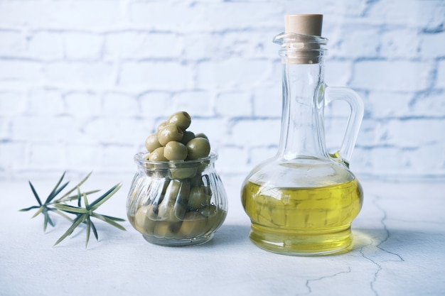 Bottle of olive oil and fresh olive in a container on wooden table