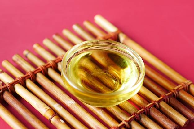 Bottle of olive oil and olive leaves on yellow