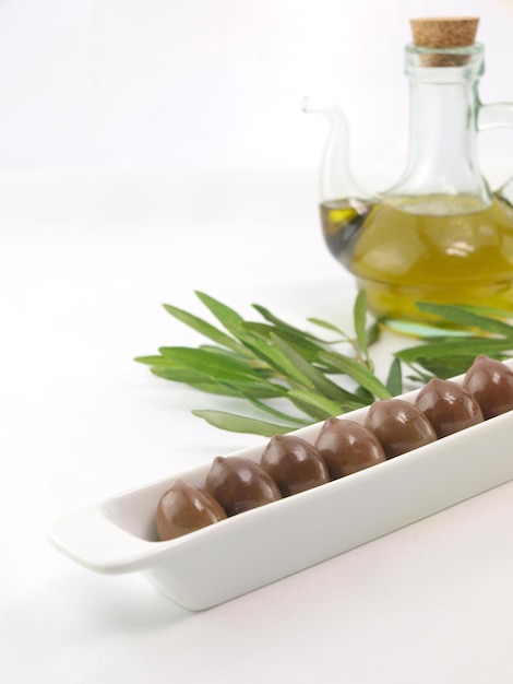 A bottle of olive oil sits next to a bowl of chocolates.