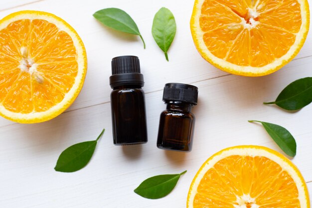 Bottle of orange essential oil  with fresh orange on white wooden 