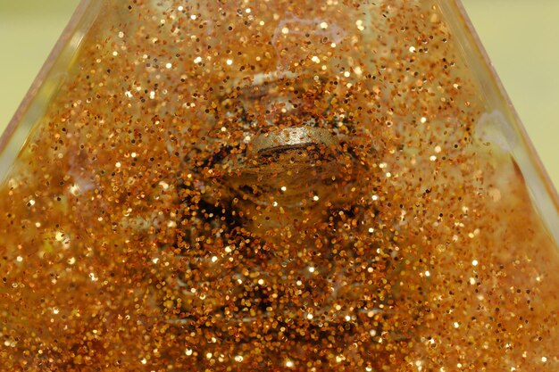 A bottle of orange glitter with a light bulb in the middle