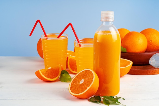 Бутылка апельсинового сока и свежих апельсинов на столе