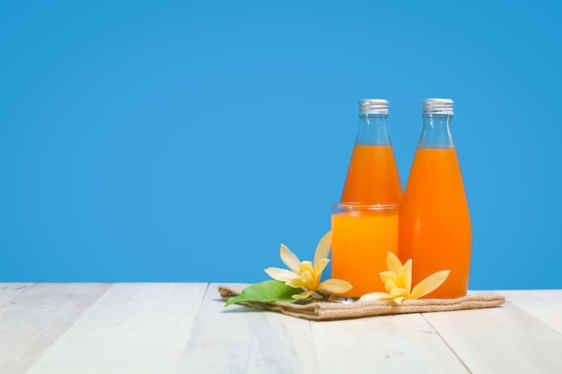 A bottle orange juice and glass  on a wooden table