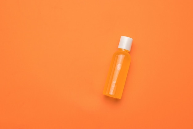 A bottle of orange juice on an orange background. Minimalism.