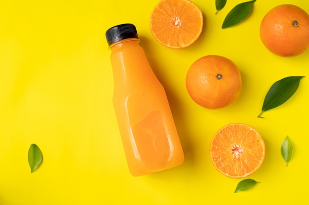 Bottle of orange juice on yellow background.