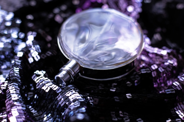 Bottle of perfume on a background of purple sequins