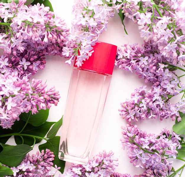 a bottle of perfume and lilac on a white surface  womens perfume spring fragrance aromatherapy