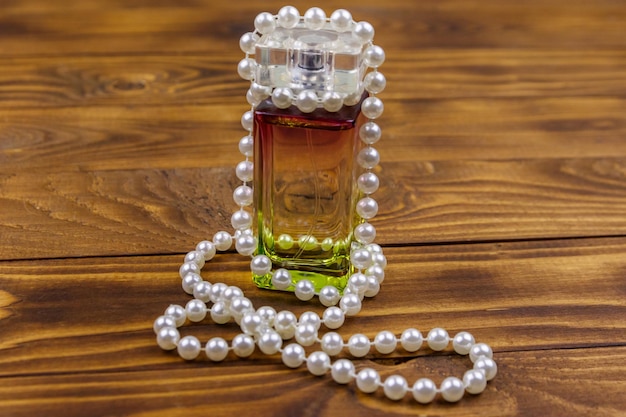 木製の背景に香水と真珠のネックレスのボトル