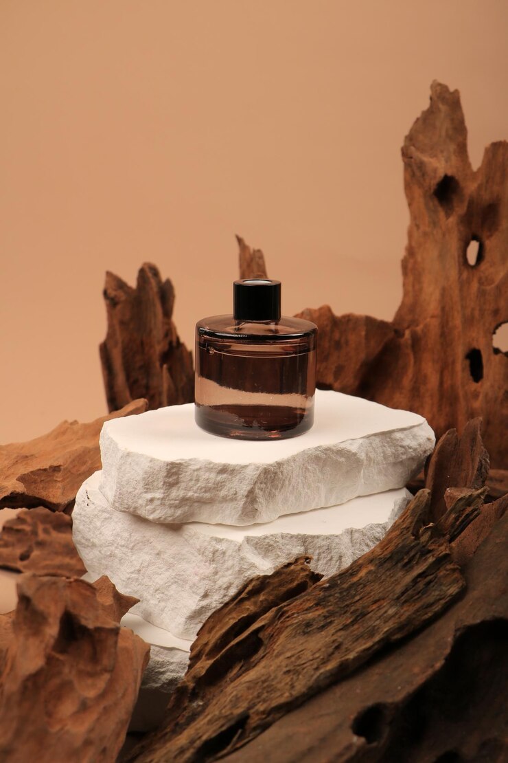 a bottle of perfume sits on a piece of driftwood