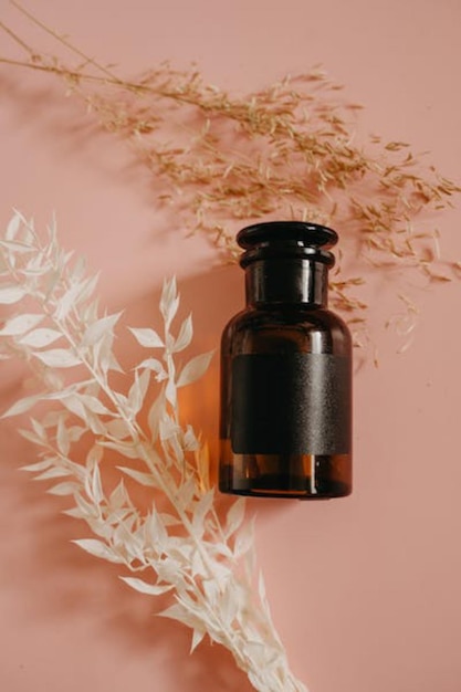 A bottle of perfume sits on a pink background.