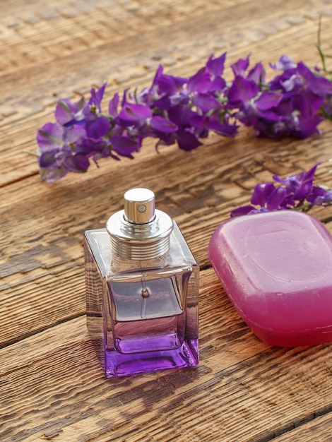 Bottle of perfume and soap on wooden boards decorated with the lilac flowers. Top view.