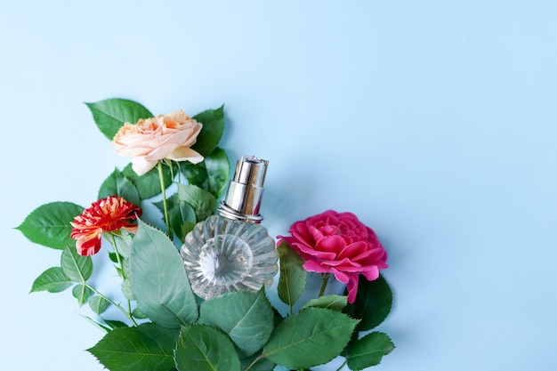 Bottle of perfume with flowers on blue