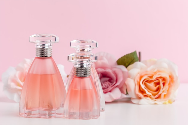 Bottle of perfume with flowers on color 