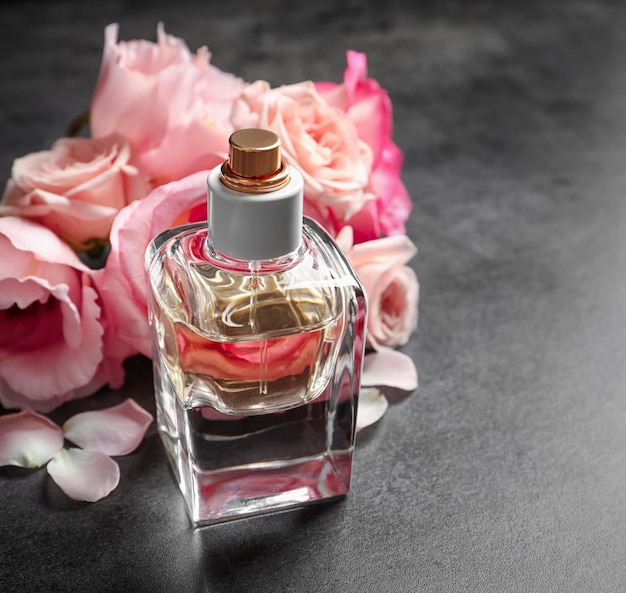 Bottle of perfume with flowers on grey background