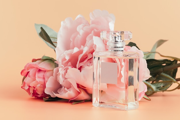 Bottle of perfume with flowers on light cloth