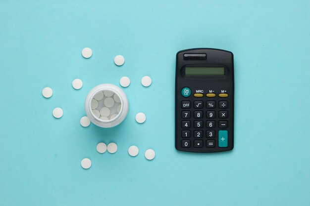 Bottle of pills, calculator on blue.