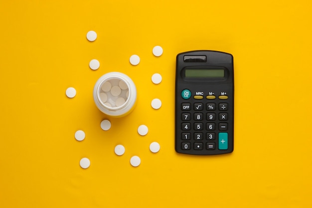 Bottle of pills, calculator on a yellow.