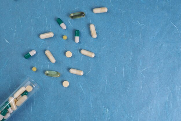 Foto una bottiglia di pillole e un bicchiere di pillole su sfondo blu