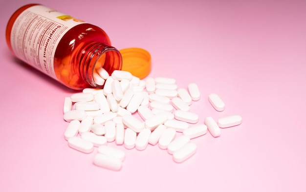 A bottle of pills is poured into a pink background.