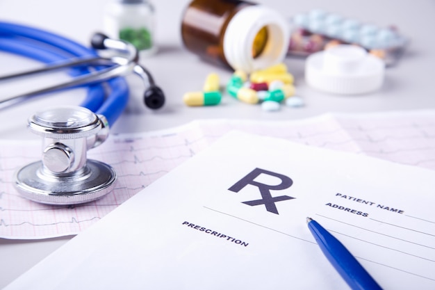 Bottle of pills and Medical stethoscope lying on cardiogram chart