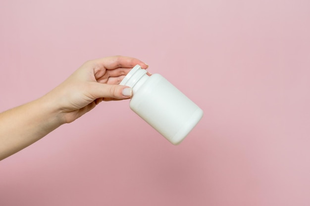 Bottle of pills or vitamins in womans hand White packaging for your pill or capsule and supplement